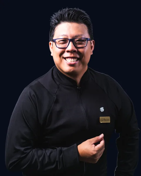 Dr. Willian Saito sorrindo, de jaleco preto da IEM